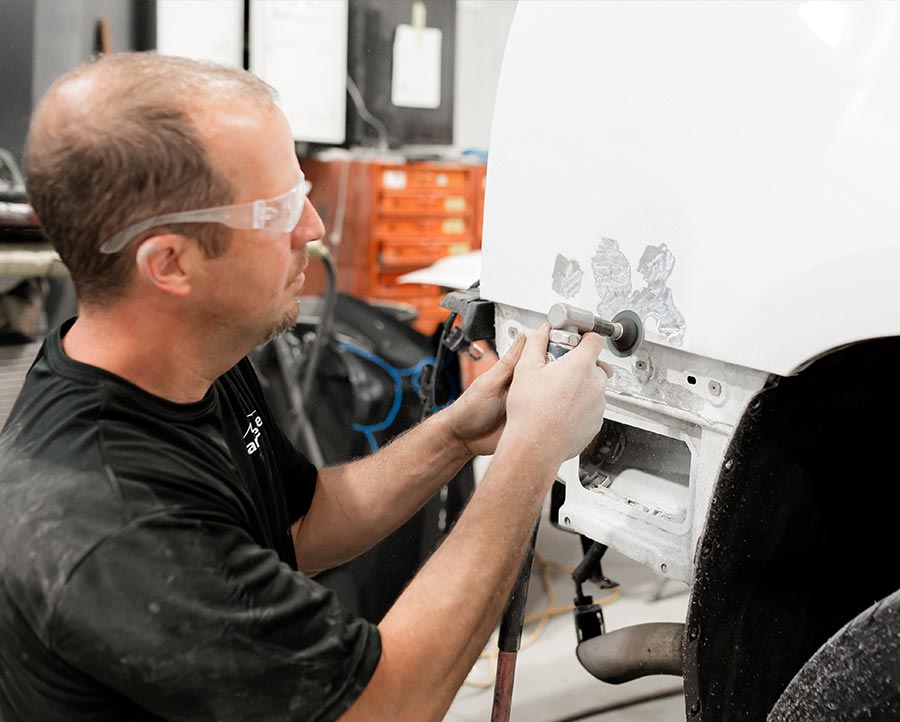 auto technician repairing truck fender at body shop in West Michigan