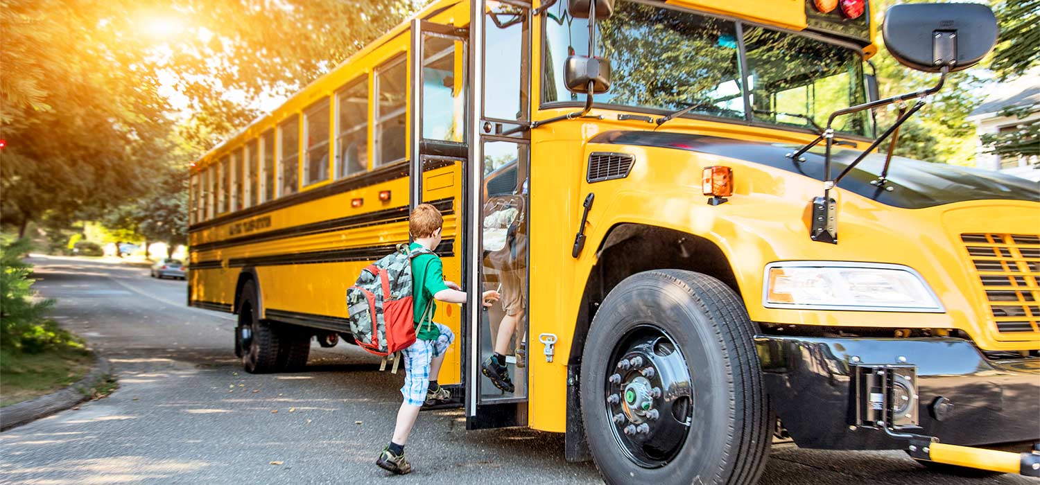child stepping onto school bus to start school year